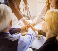 Groupe personnes joignant mains sur bureau